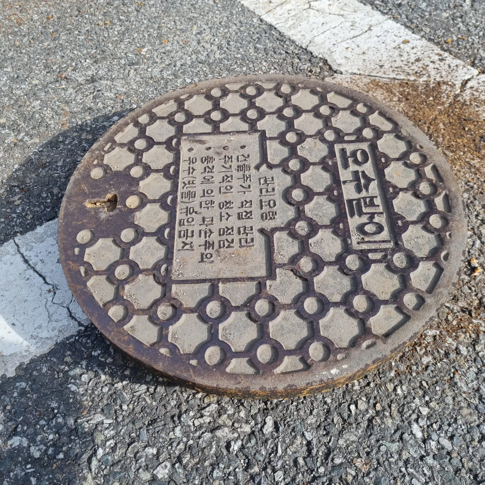 노면에 내려놓은 둥근 뚜껑 윗면에 오수받이라는 글자와 관리요령 문구가 새겨져 있다